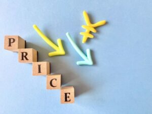 PRICEと書かれた木製ブロックと下向きの矢印と円マークが並ぶ値下げのイメージ画像