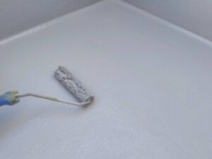 ベランダ床面に白色防水塗料をローラーで均一に塗る